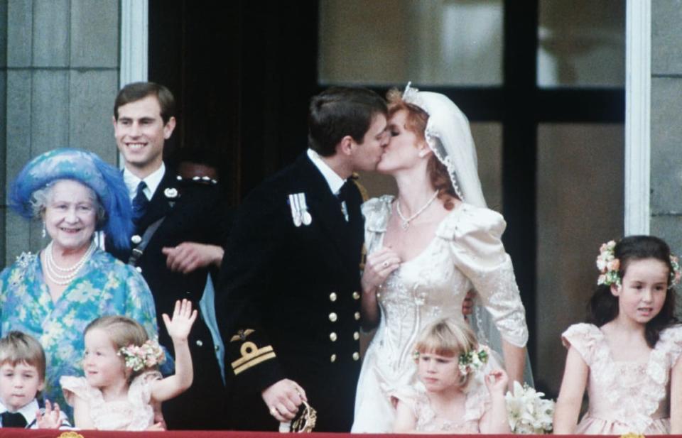 Prince Andrew is seen kissing Sarah Ferguson on the balcony, after their wedding ceremony at Buckingham Palace in this photo. Queen Elizabeth the Queen Mother and Prince Edward stand to the right of the couple.