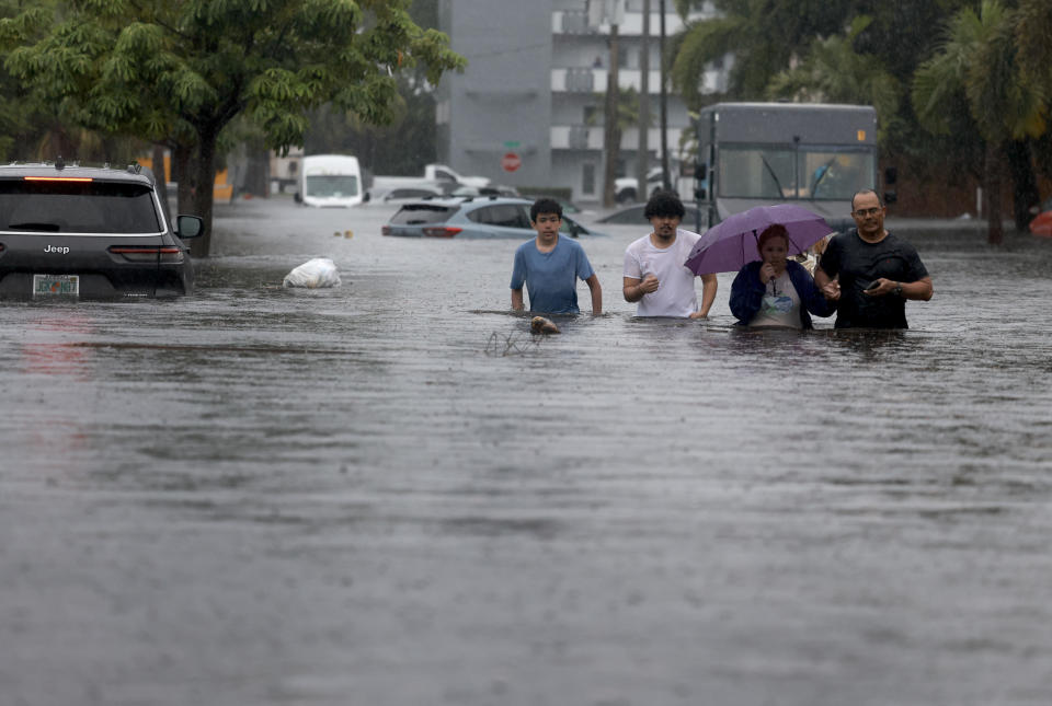 People walk through a flooded street as they evacuate on June 12, 2024, in Hollywood, Florida. / Credit: Joe Raedle/Getty Images