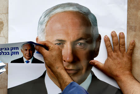 A Likud party supporter puts up a poster depicting party leader Benjamin Netanyahu in the northern Druze village of Yarka, Israel February 8, 2009. REUTERS/Ammar Awad