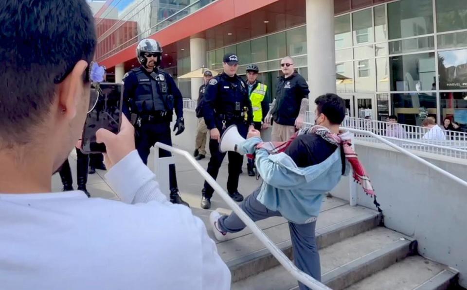 While a student videos, Cal Poly student Samir Ibrahim reaches his foot out onto the top step outside the Cal Poly Rec Center after police told protesters to leave following a clash between officers and pro-Palestine demonstrators on Tuesday, Jan. 23, 2024.