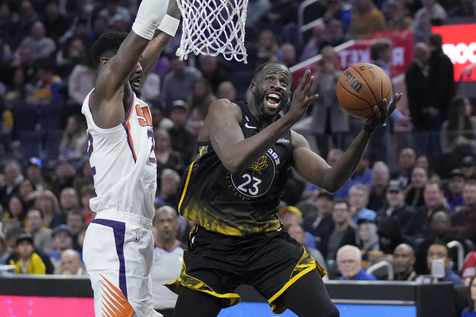 Golden State Warriors forward Draymond Green (23) scores against Phoenix Suns center Deandre Ayton during the first half of an NBA basketball game in San Francisco, Monday, March 13, 2023. (AP Photo/Jeff Chiu)