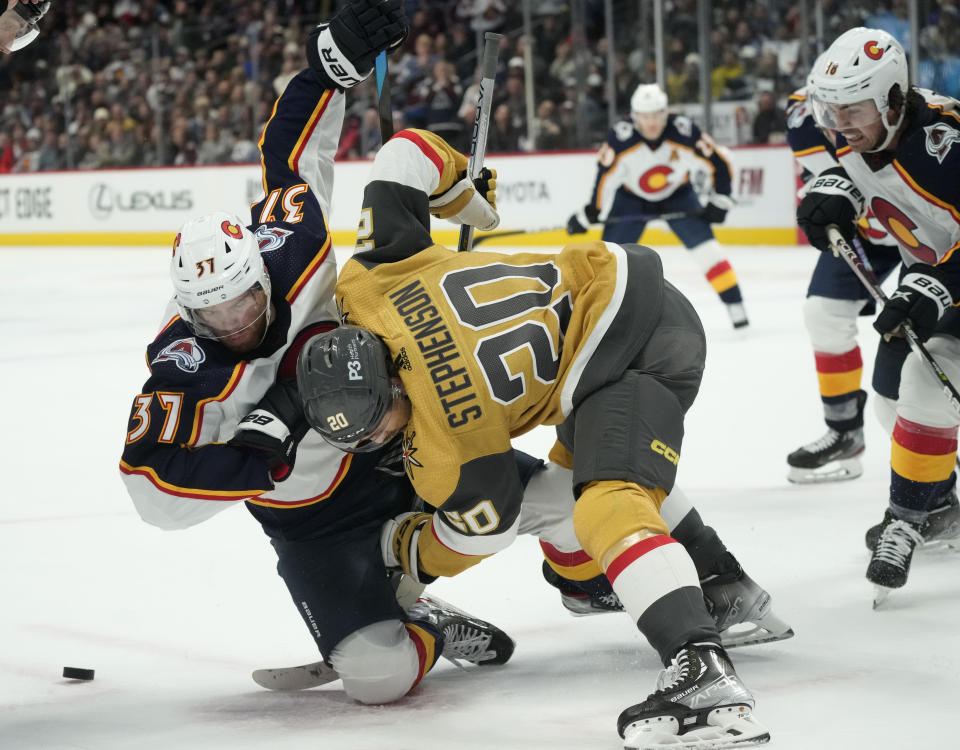 Vegas Golden Knights center Chandler Stephenson, front, battles for control of the puck with Colorado Avalanche left wing J.T. Compher in the third period of an NHL hockey game Monday, Jan. 2, 2023, in Denver. (AP Photo/David Zalubowski)