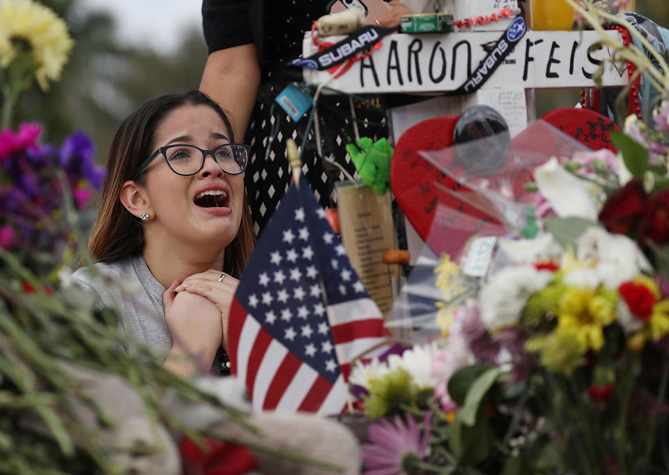 <p>Ariana Gonzalez is over come with emotion as she visits a cross setup for her friend, football coach Aaron Feis, at the memorial in front of Marjory Stoneman Douglas High School as teachers and staff are allowed to return to the school for the first time since the mass shooting on campus on February 23, 2018 in Parkland, Fla. (Photo: Joe Raedle/Getty Images) </p>