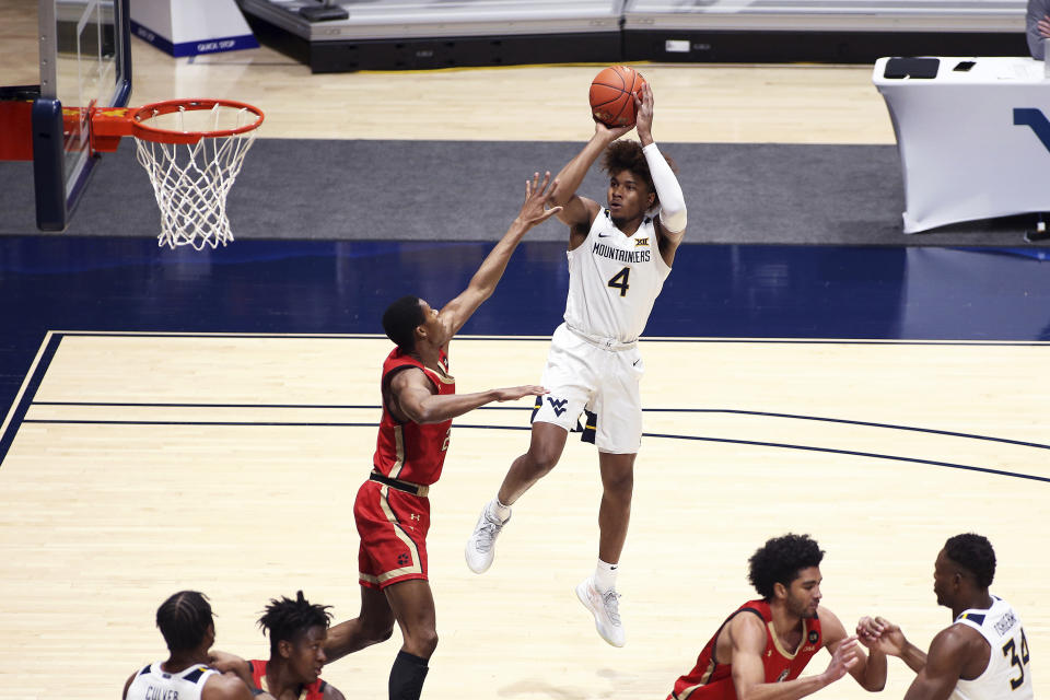 West Virginia guard Miles McBride (4) shoots while defended by Northeastern guard Shaquille Walters (24) during the first half of an NCAA college basketball game Tuesday, Dec. 29, 2020, in Morgantown, W.Va. (AP Photo/Kathleen Batten)