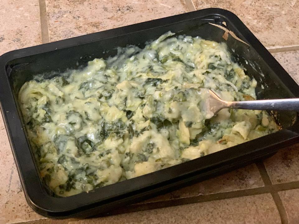 Cooked trader joe's creamed greens stirred with fork on kitchen counter