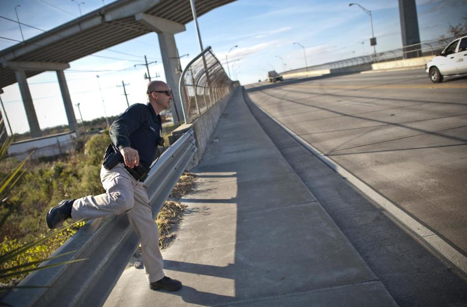 In this Thursday, Dec. 19, 2013 photo, Homeless Liaison Officer Tom Gentner climbs over highway railing after visiting a camp underneath while on his daily rounds to 20 homeless camps surrounding the Historic District in Savannah, Ga. The homeless in Savannah live under highway bridges, ramps, and the urban forest surrounding downtown. Part of Gentner's job is to document newcomers and check criminal activity. (AP Photo/Stephen B. Morton)