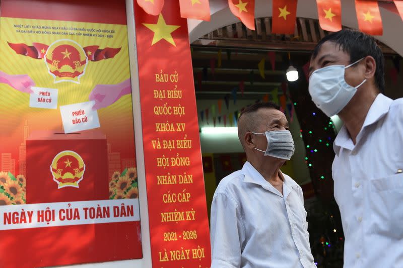 People stand around a place that will be a polling station for the upcoming elections in Hanoi