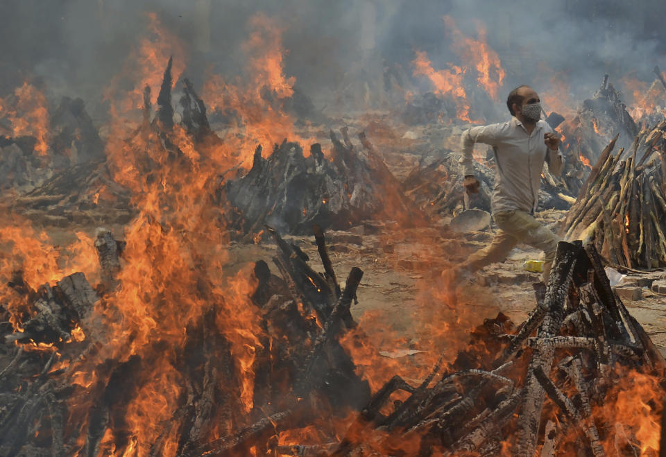 A man runs to escape heat emitting from the multiple funeral pyres of COVID-19 victims at a crematorium in the outskirts of New Delhi, India, Thursday, April 29, 2021. (AP Photo/Amit Sharma)