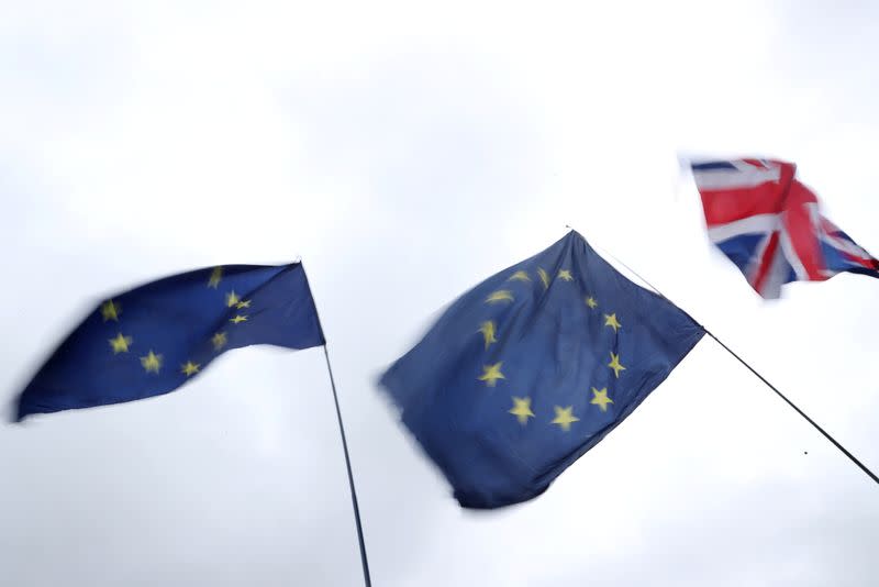 A Union Jack flag flutters next to EU flags outside the Houses of Parliament in London