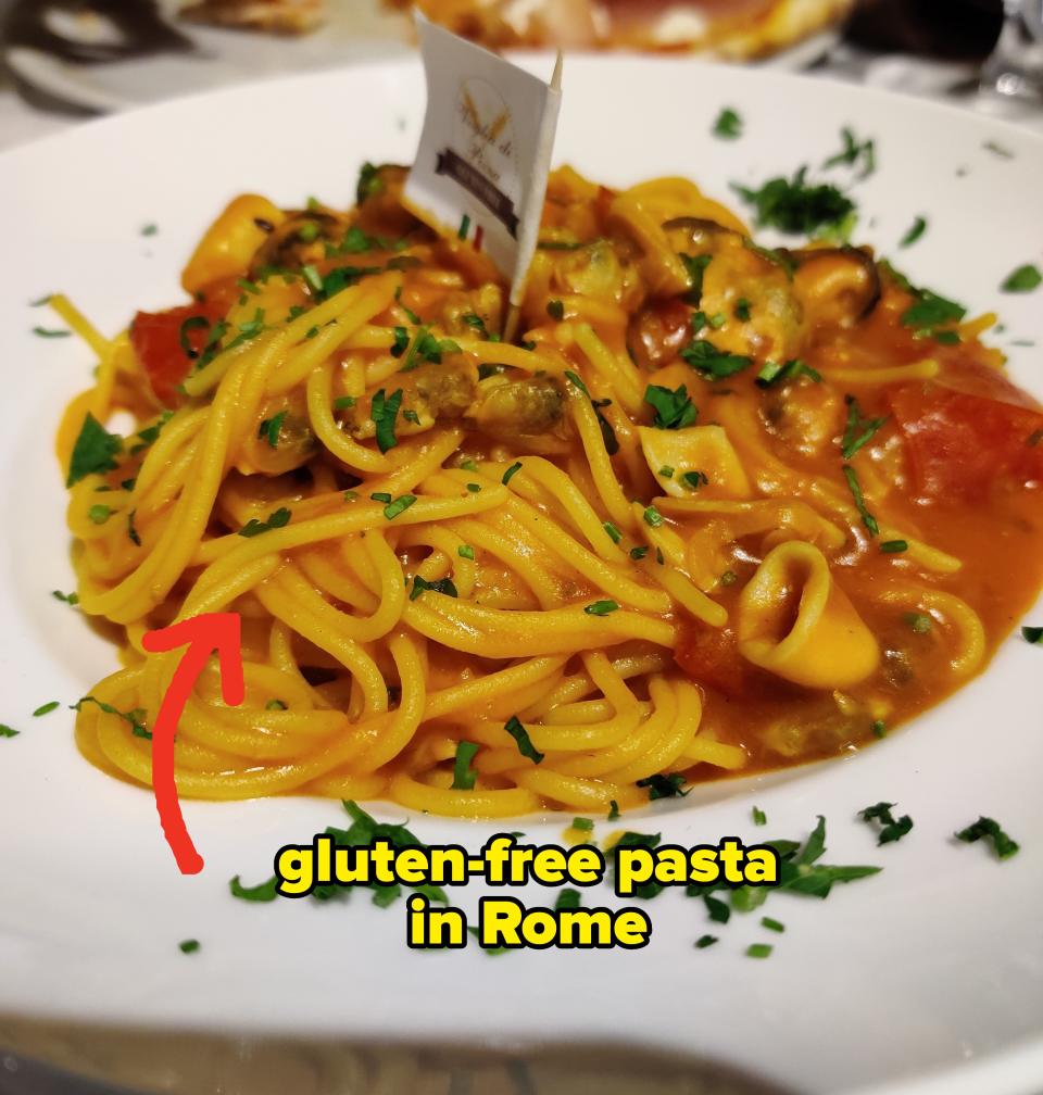 A plate of pasta with tomato sauce and chopped herbs on a table, suggesting Italian cuisine