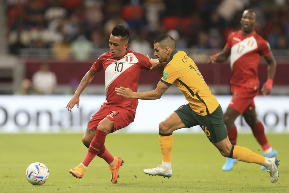 El peruano Christian Cueva (izquierda) y el australiano Aziz Behich pugnan por el balón en el repechaje intercontinental por una plaza a la Copa Mundial, en Al Rayyan, Qatar, el lunes 13 de junio de 2022. (AP Foto/Hussein Sayed)