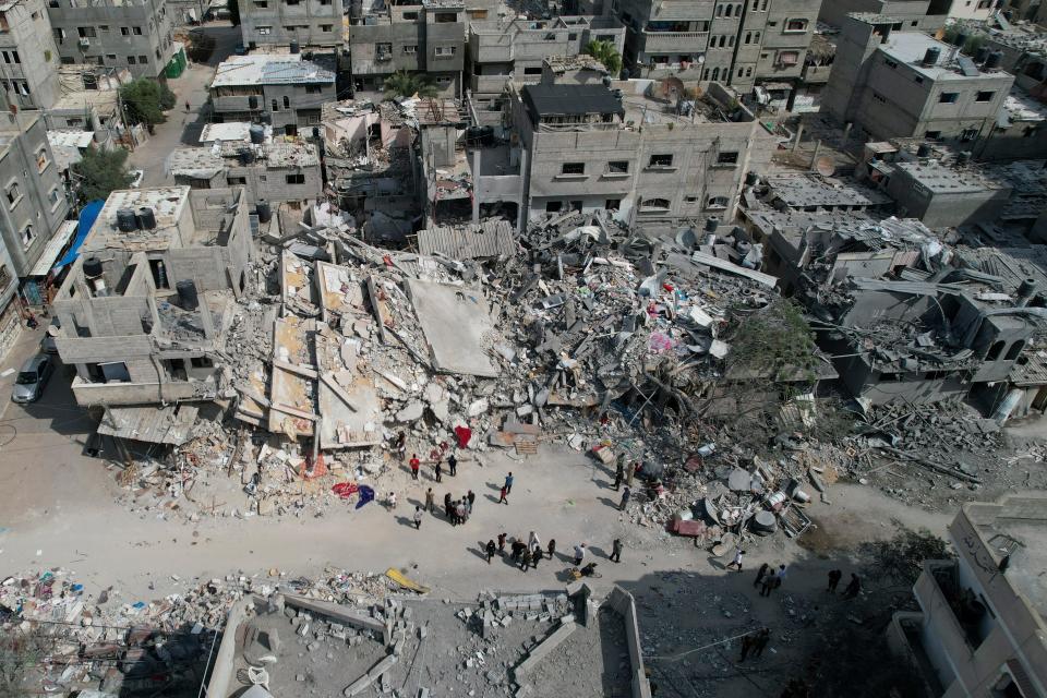 Palestinians stand by a building destroyed in an Israeli airstrike in Nuseirat camp in the central Gaza Strip on Oct. 16, 2023.