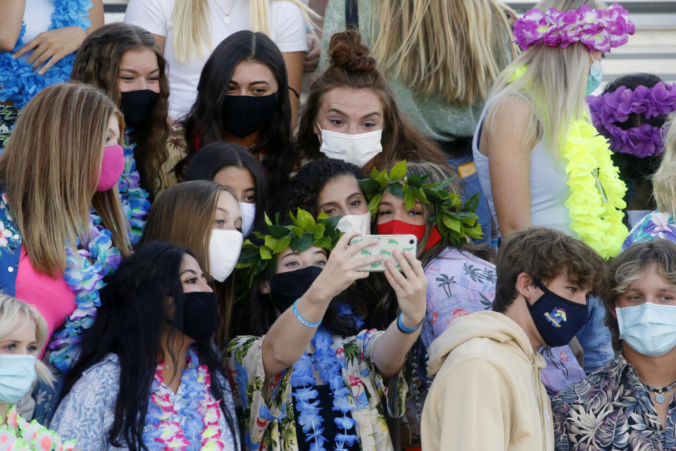 A group of Herriman fans take a selfie during a high school football game against Davis on Thursday, Aug. 13, 2020, in Herriman, Utah. Utah is among the states going forward with high school football this fall despite concerns about the ongoing COVID-19 pandemic that led other states and many college football conferences to postpone games in hopes of instead playing in the spring. (AP Photo/Rick Bowmer)