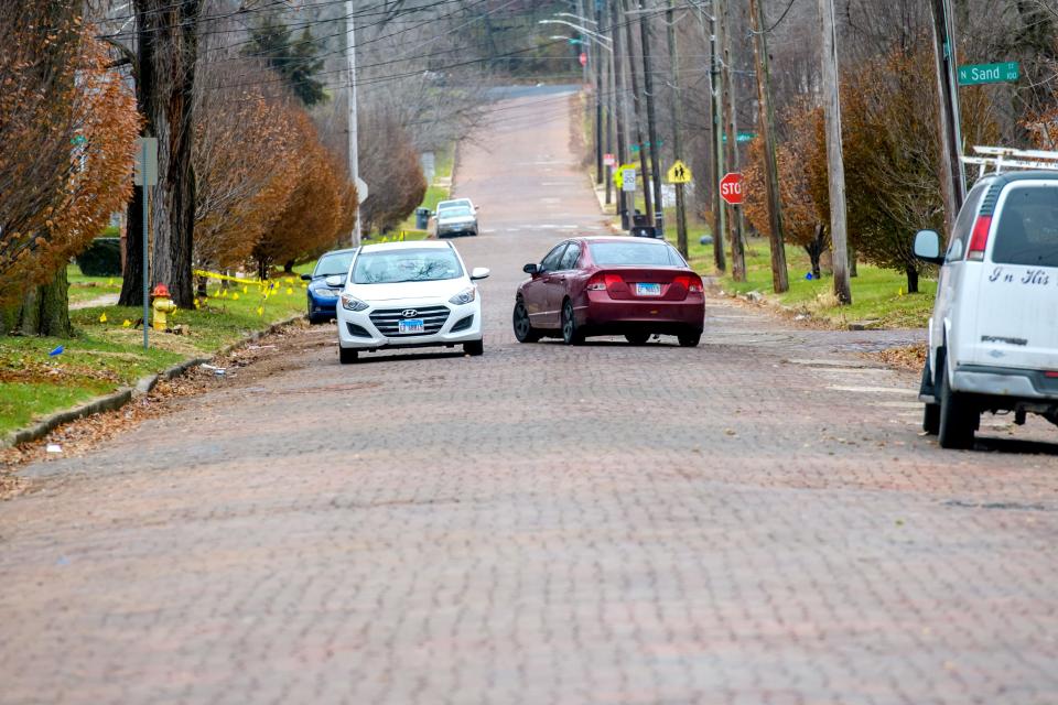 A vehicle switches lanes to avoid a large damaged area of brick paves at N. Sand Street and W. Aiken Avenue in South Peoria.