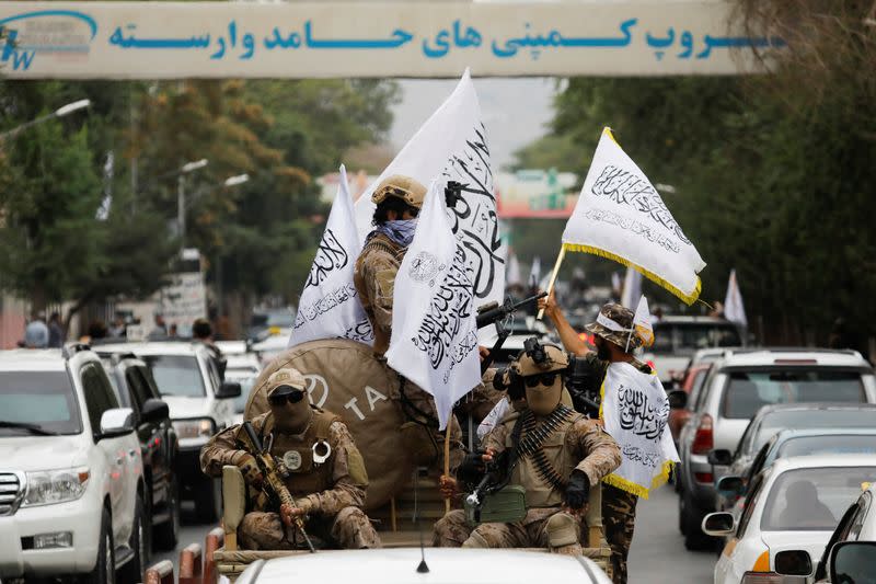 Taliban supporters hold Islamic Emirate of Afghanistan flags on the first anniversary of the fall of Kabul