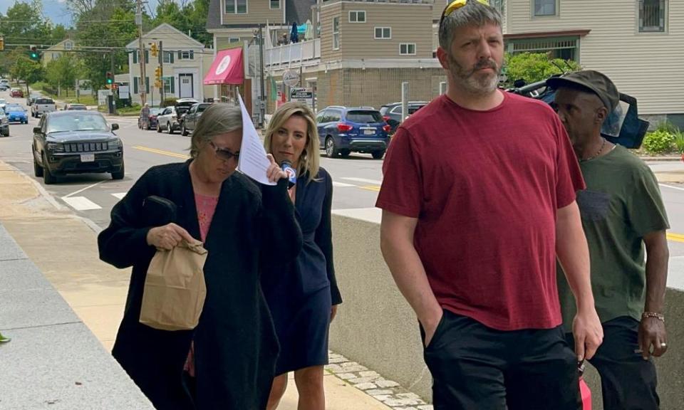 Denise Lodge, left, covers her face with a printout of the indictment against her as she walks from the federal courthouse in Concord, New Hampshire, on Wednesday.