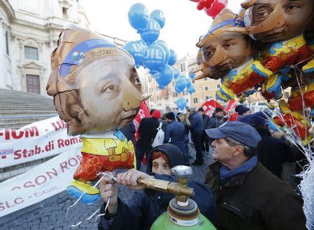 A woman inflates a balloon depicting the puppet Pinocchio with the face of Italian Prime Minister Matteo Renzi during a demonstration against government in downtown Rome December 12, 2014. REUTERS/Remo Casilli