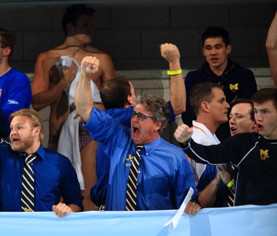 University of Michigan Swimming and Diving coach Mike Bottom (center) cheers on his team as they compete in the NCAA championships on March 28, 2015.