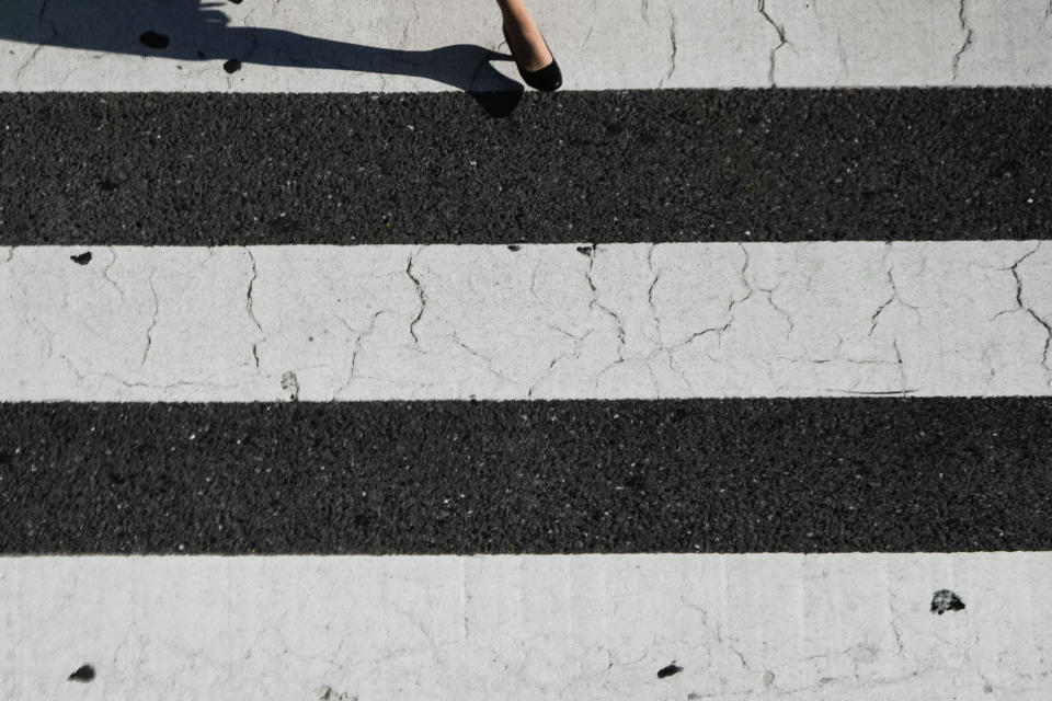 A woman steps onto the famous Shibuya crossing Thursday, June 13, 2019, in Tokyo. It's not just a crossing. Located just outside Shibuya Station, the scramble crossing is one of the top tourist attractions in Japan. It's so famous that there's an observation deck on the rooftop of a building built to watch the crossing. During rush hour, an estimated 1000 to 2500 people cross the intersection during each traffic light change. (AP Photo/Jae C. Hong)