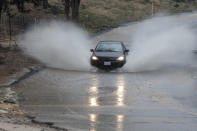 A car hits a deep section of rain run off along Peach Avenue in Hesperia, Calif., Thursday, Jan. 17, 2019. (James Quigg/The Daily Press via AP)