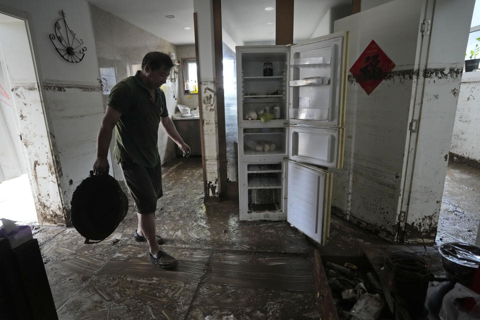 A resident clears mud from his home after floods devastated Nanxinfang village on the outskirts of Beijing, Friday, Aug. 4, 2023. Heavy rain and high water levels on rivers in northeastern China were threatening cities downstream on Friday, prompting the evacuation of thousands, although the country appears to have averted the worst effects of the typhoon season battering parts of east Asia. (AP Photo/Ng Han Guan)