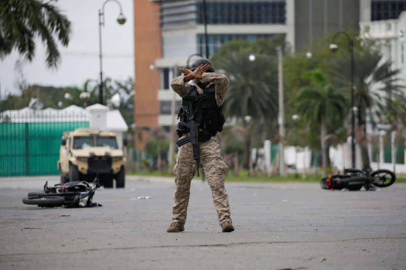 A Haitian National Police officer gestures to calm down protesters during a shooting in Champ de Mars, Port-au-Prince