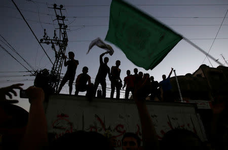 FILE PHOTO - A Palestinian waves a Hamas flag (R) in Gaza City August 26, 2014. REUTERS/Suhaib Salem/File Photo