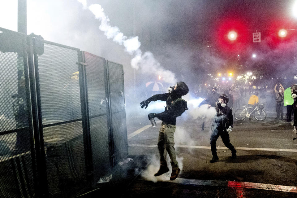 A Black Lives Matter protester lobs a projectile back at federal officers guarding the Mark O. Hatfield United States Courthouse on Friday, July 24, 2020, in Portland, Ore. Since federal officers arrived in downtown Portland in early July, violent protests have largely been limited to a two block radius from the courthouse. (AP Photo/Noah Berger)