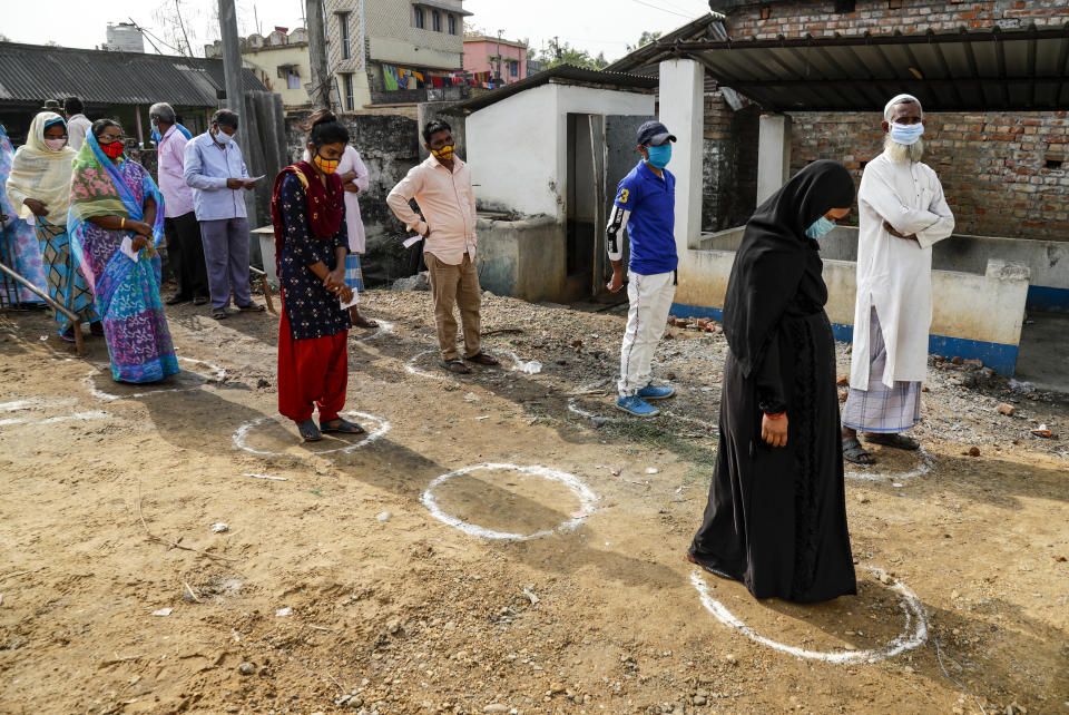 Voters stands on marked areas maintaining social distance as they wait to cast their votes at a polling booth during first phase elections in West Bengal state in Salboni, India, Saturday, March 27, 2021. Voting began Saturday in two key Indian states with sizeable minority Muslim populations posing a tough test for Prime Minister Narendra Modi’s popularity amid a months-long farmers’ protest and the economy plunging with millions of people losing jobs because of the coronavirus pandemic. (AP Photo/Bikas Das)