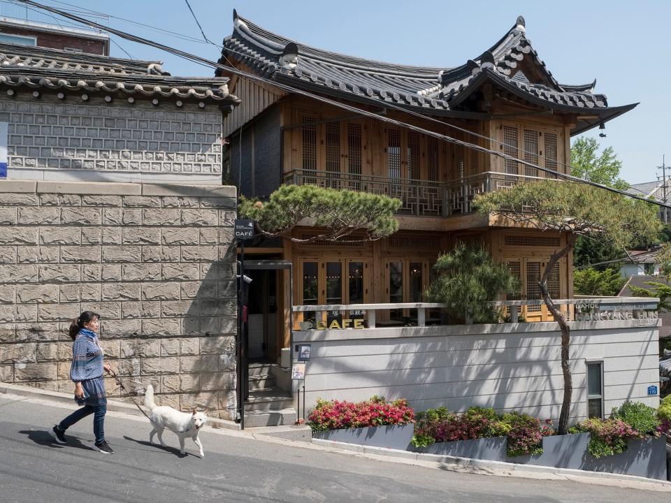 A woman walks a dog in the South Korean village of Bukchon Hanok.