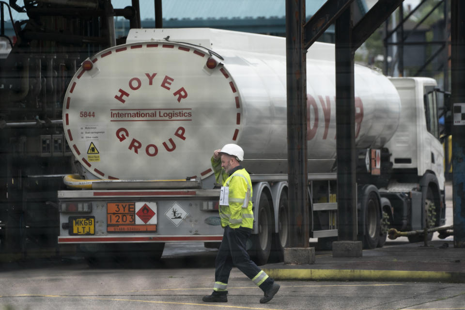 A worker walks by a fuel tanker at the Valero Manchester Terminal, in Manchester, England, Tuesday, Sept. 28, 2021. Thousands of British gas stations have run dry, as motorists scrambled to fill up amid a supply disruption due to a shortage of truck drivers. Long lines of vehicles formed at many gas stations over the weekend, and tempers frayed as some drivers waited for hours. (AP Photo/Jon Super)