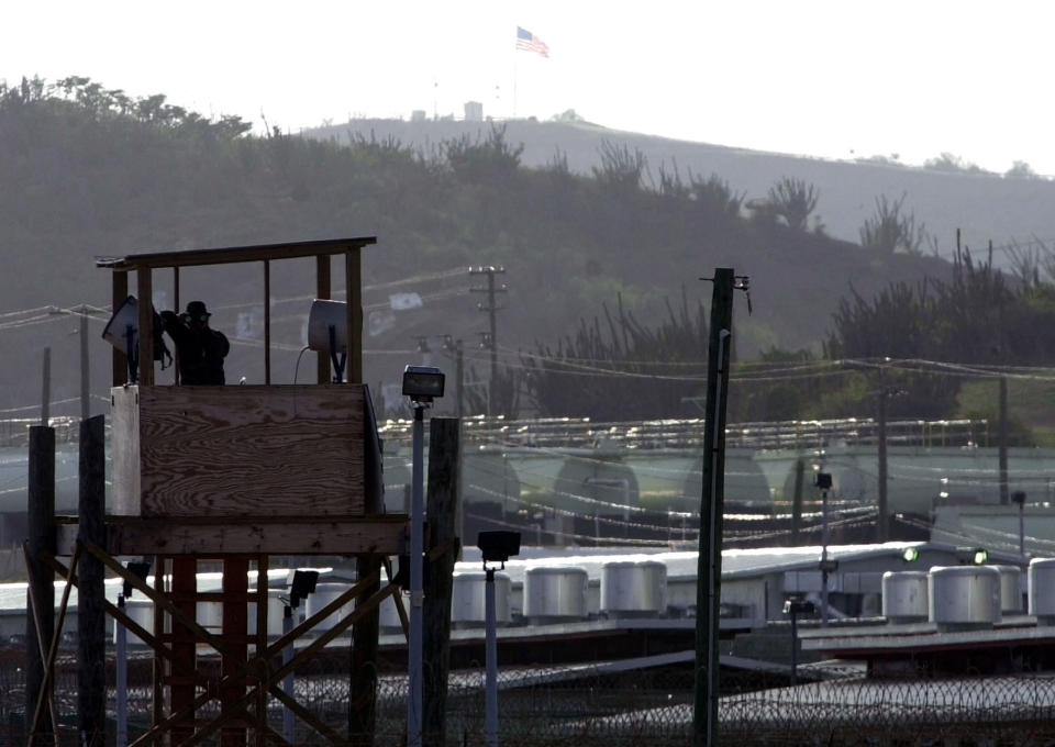 FILE - In this Sept. 10, 2002, file photo a U.S. Army military police officer looks through binoculars from a guard tower at Camp Delta where 598 detainees from some 43 countries are being held at the U.S. Naval Base at Guantanamo Bay, Cuba. The White House says it intends to shutter the prison on the U.S. base in Cuba, which opened in January 2002 and where most of the 39 men still held have never been charged with a crime. (AP Photo/Lynne Sladky, File)