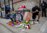 People gather and pray around a makeshift memorial, Tuesday, May 26, 2020, in Minneapolis, near the site where a black man, who was taken into police custody the day before, later died. The FBI and Minnesota agents are investigating the death of a black man in Minneapolis police custody after video from a bystander showed a white officer kneeling on his neck during his arrest as he pleaded that he couldn't breathe. (Elizabeth Flores/Star Tribune via AP)