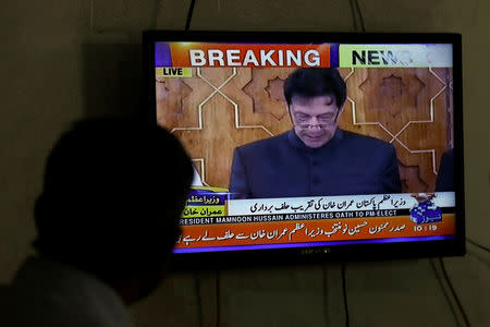 A man looks at a television screen displaying cricketer-turned-politician Imran Khan swearing in as Prime Minister of Pakistan, in Karachi, Pakistan August 18, 2018. REUTERS/Akhtar Soomro