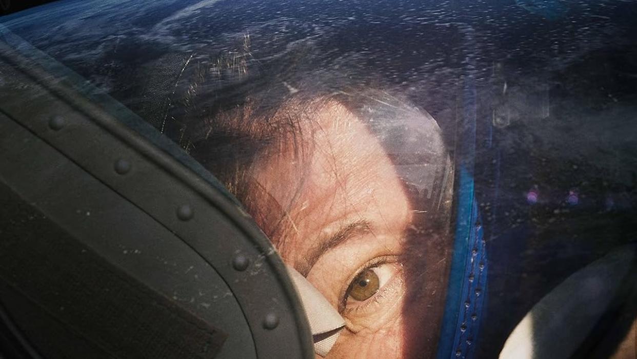  A person's eye can be seen looking through the glass of a spacesuit helmet. stars can be seen filling the background. 