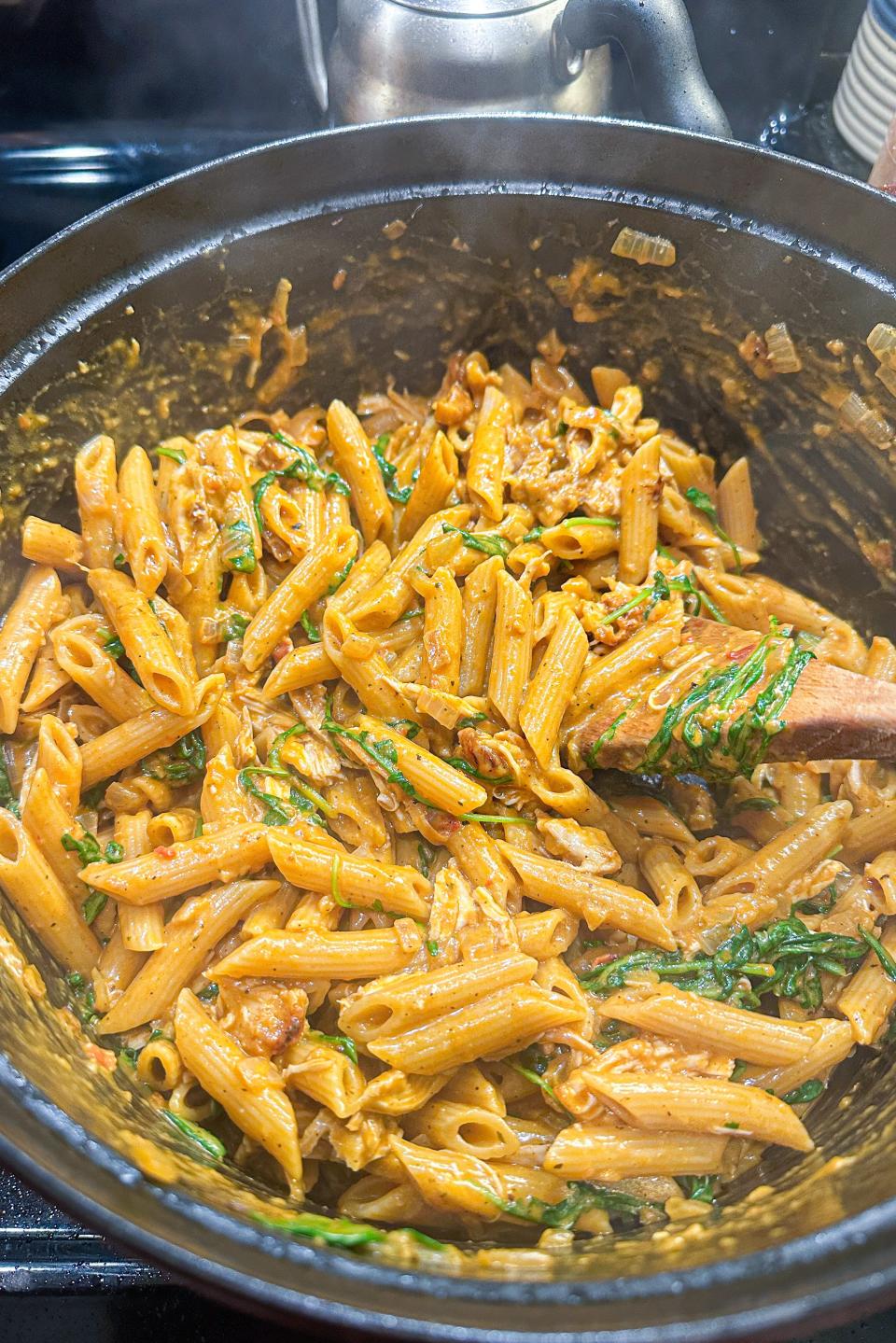 Cooked pasta with sauce and herbs in a skillet on a stove