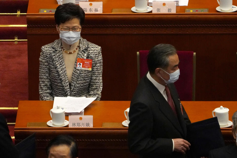 Hong Kong Chief Executive Carrie Lam sits as Chinese Foreign Minister Wang Yi, right, arrives before the opening session of China's National People's Congress (NPC) at the Great Hall of the People in Beijing, Friday, March 5, 2021. (AP Photo/Andy Wong)