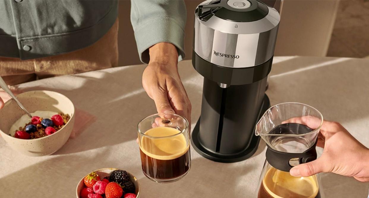 people holding cups of coffee beside the machine and bowls of fruit