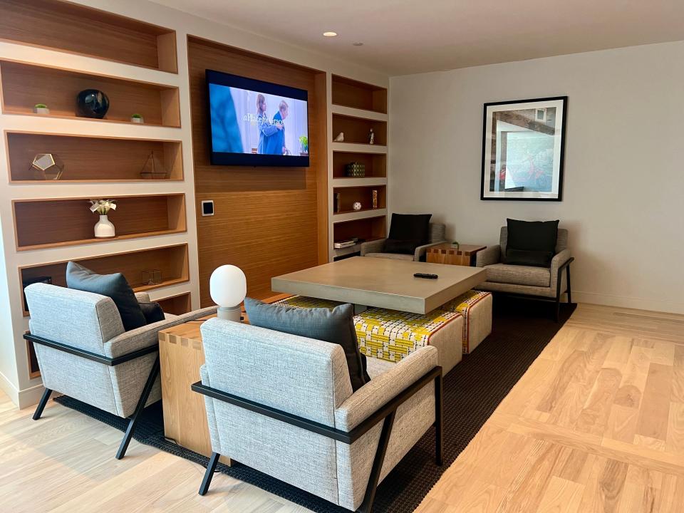 The lounge with gray chairs, shelves, and a tv.