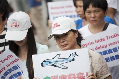 People whose relatives were aboard Malaysia Airlines flight MH370 hold placards as they protest near the Malaysian embassy in Beijing August 7, 2015. REUTERS/Damir Sagolj