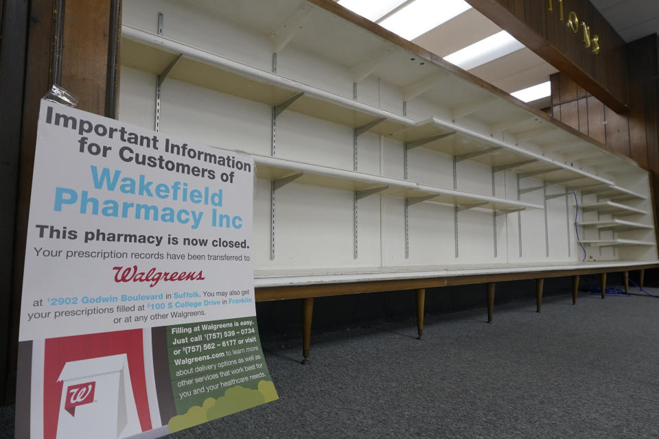 A sign informing customers that the pharmacy is closed sits in an empty store in Wakefield, Va., Tuesday, Feb. 9, 2021. Getting the coronavirus vaccine has been a challenge for rural counties in the U.S. that lack medical facilities such as a pharmacy or a well-equipped doctor's office. (AP Photo/Steve Helber)