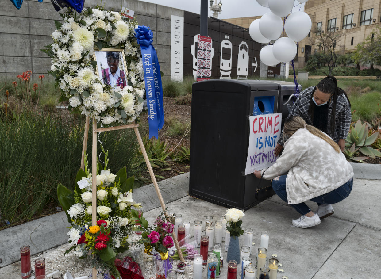 Samantha Mesa and Terri Thompson hang a sign near a bus stop. 