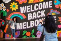 People take photos in front of a 'Welcome Back' sign after coronavirus disease restrictions were eased in Melbourne