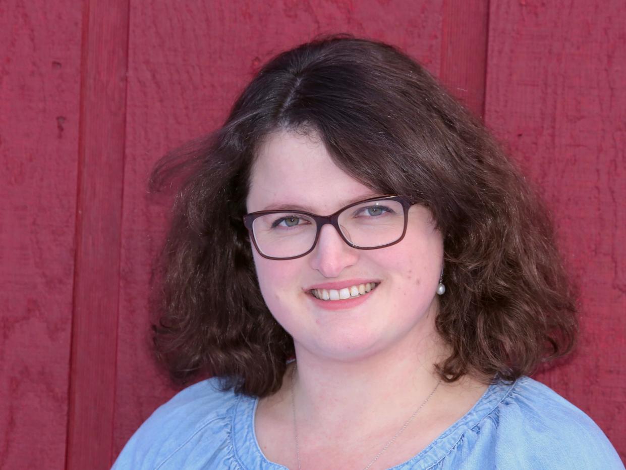 The author, Laura Ojeda Melchor, smiling at the camera against a red wall