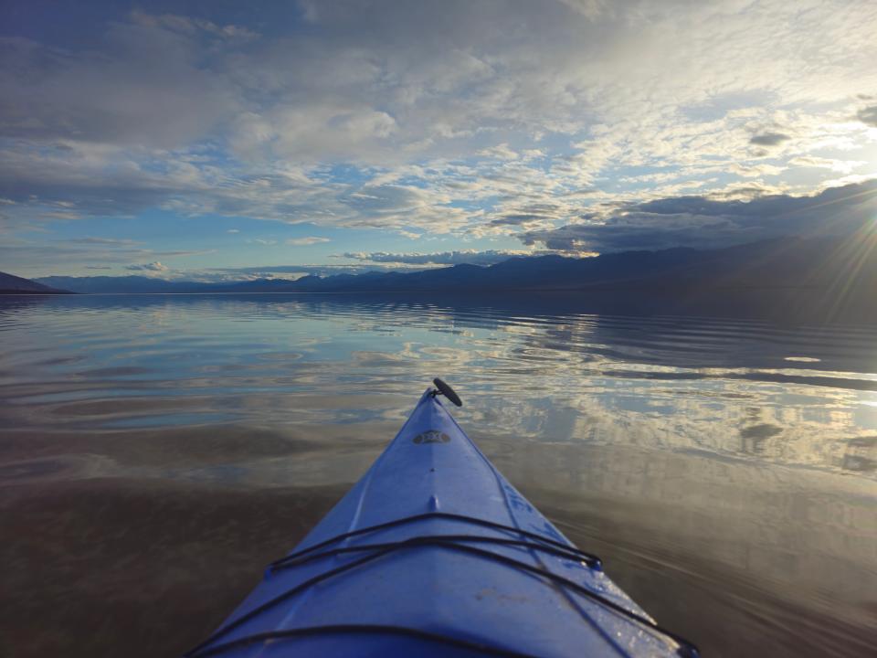 A kayak glides over the smooth surface of an ephemeral lake that appeared at Death Valley National Park after Hurricane Hilary and surprised the parkgoers by lingering for several months.