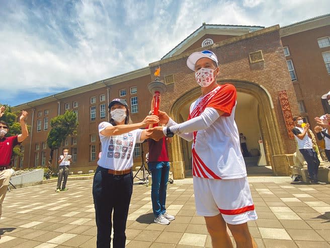 成功大學睽違40年再度主辦全國大專院校運動會，首度以跑步完成19天1168公里環台聖火傳遞，8日聖火隊跑抵成大，由成大造船系73級校友陳財富（右）將聖火交給校長蘇慧貞。（曹婷婷攝）