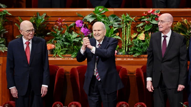 President Russell M. Nelson of The Church of Jesus Christ of Latter-day Saints clasps his hands and gestures toward the audience as he and his counselors, President Dallin H. Oaks, first counselor in the First Presidency, left, and President Henry B. Eyring, second counselor in the First Presidency, take their seats prior to the afternoon session of the 194th Annual General Conference of The Church of Jesus Christ of Latter-day Saints at the Conference Center in Salt Lake City on Sunday, April 7, 2024.