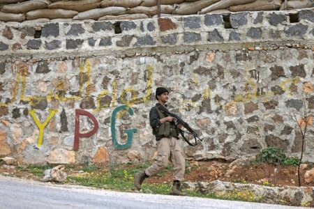 Turkish-backed Free Syrian Army fighter walks as he holds his weapon near the city of Afrin, Syria February 21, 2018. REUTERS/Khalil Ashawi