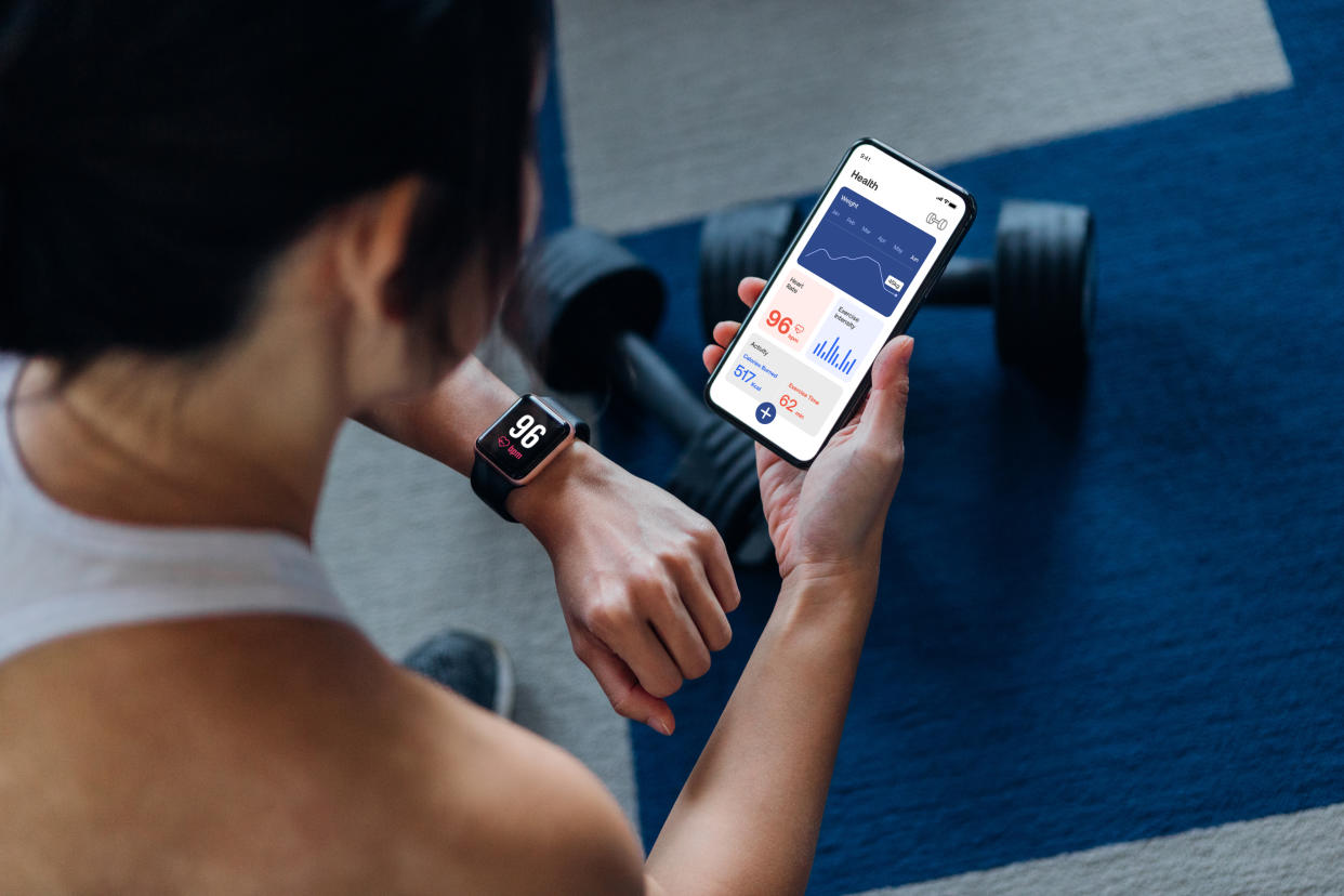 A woman checks her wearable, which is monitoring her health indicators. Getty Creative. 