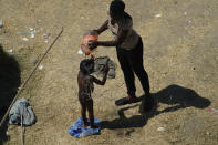 A young migrant gets a bath at a make-shift camp along the Rio Grande after crossing into the United States from Mexico, Friday, Sept. 17, 2021, in Del Rio, Texas. Thousands of Haitian migrants have assembled under and around a bridge in Del Rio presenting the Biden administration with a fresh and immediate challenge as it tries to manage large numbers of asylum-seekers who have been reaching U.S. soil. (AP Photo/Eric Gay)